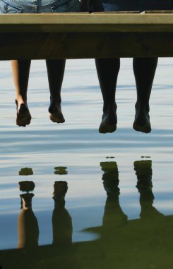 Two People Dangling Their Feet Off A Dock clipart