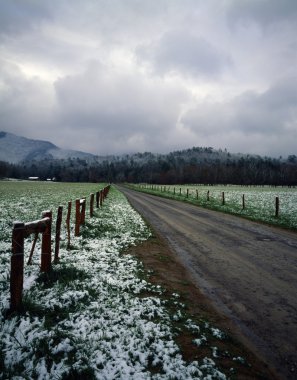 Spring Snow On Fields And Fence Row, Dirt Road, Distant Mountains In Fog, Cades Cove, Great Smoky Mountains National Park clipart