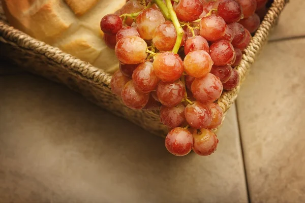 Un primer plano de uvas rojas y una barra de pan — Foto de Stock