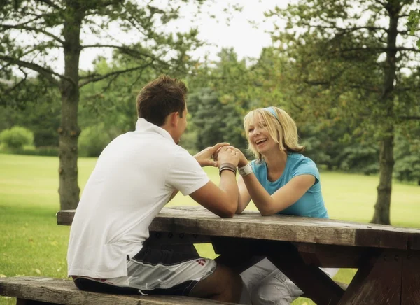 Jonge paar zitten op een picknicktafel — Stockfoto