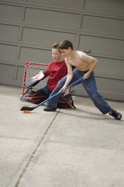 Boys Playing Hockey On Driveway clipart