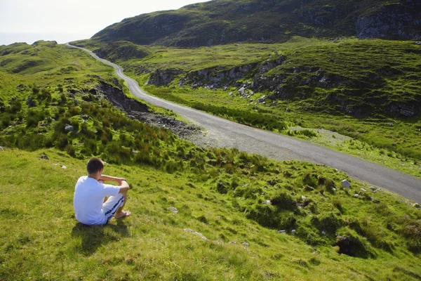 Homme assis à côté de la route — Photo