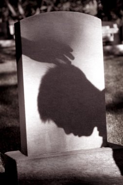 Shadow Of Hand Over Head Of Grieving Man At Grave Site clipart