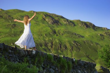 Young Woman Balancing On Rock Wall Ledge clipart