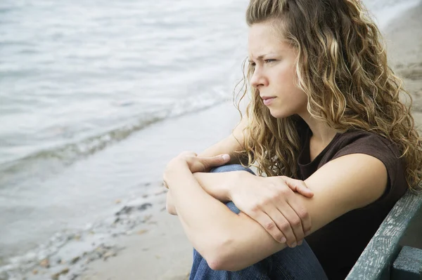 Eine junge erwachsene Frau reflektiert am Strand — Stockfoto