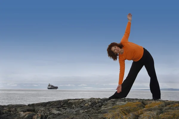 Woman Stretching On A Rocky Beach — Stock Photo, Image