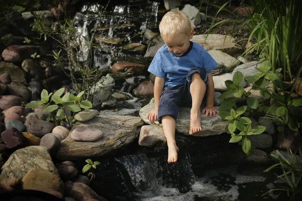 Jongen door tuin waterfall — Stockfoto