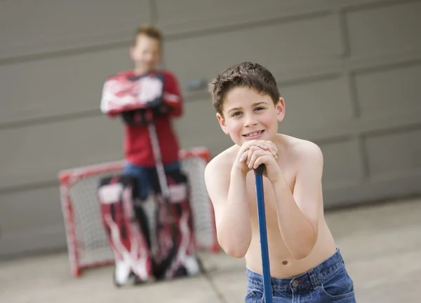 Мальчик опирается на свою хоккейную клюшку — стоковое фото