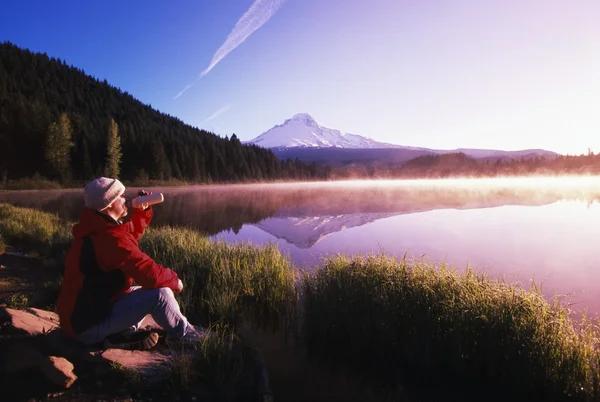 Persona seduta in riva al lago di montagna — Foto Stock