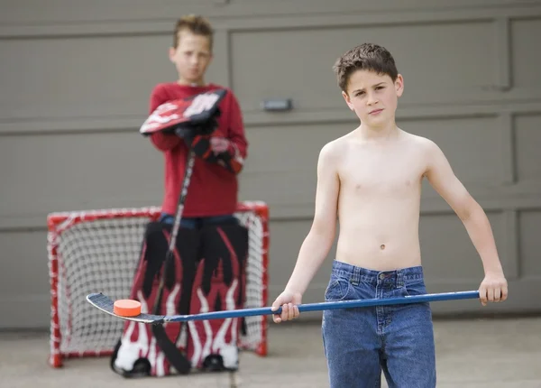 Een jongen berust een puck op zijn hockeystick — Stockfoto