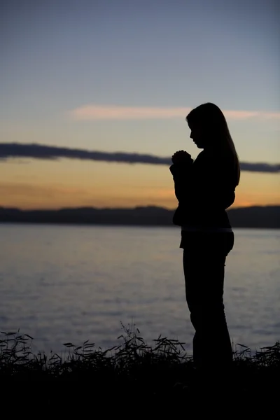 Ein Teenager-Mädchen betet bei Sonnenuntergang am Meer. — Stockfoto