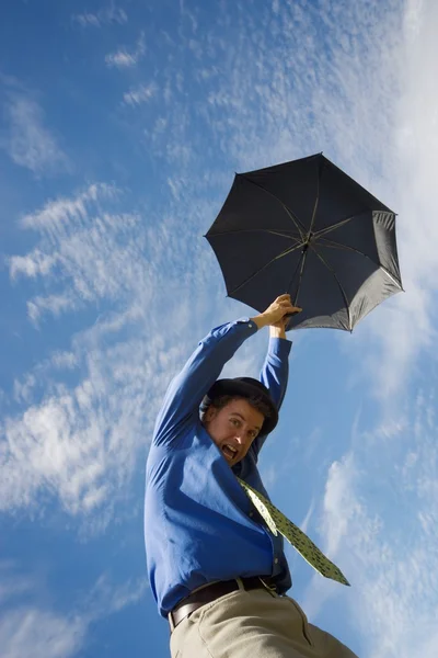 Homem segurando guarda-chuva flutuando até o céu — Fotografia de Stock