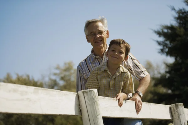 Дедушка и внук на улице, опираясь на забор — стоковое фото