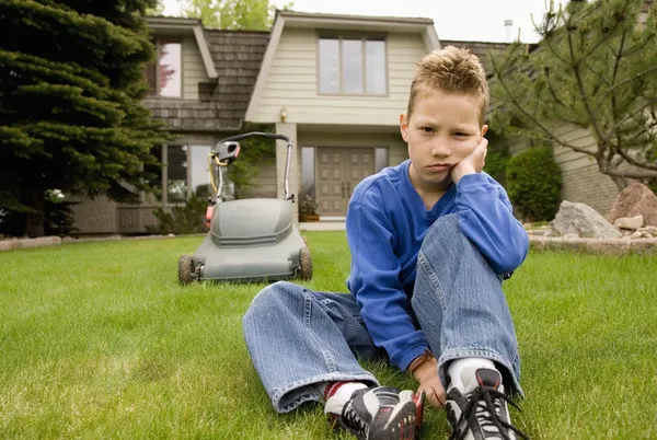 Een jongen mokt en vermijdt het maaien van het gras — Stockfoto