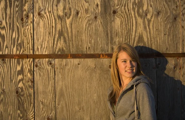 Jonge vrouw staat tegen oude houten gebouw — Stockfoto