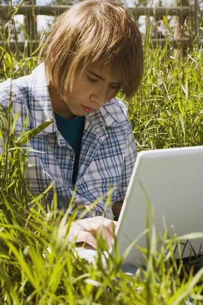 Teen Using Laptop In Tall Grass Stock Photo