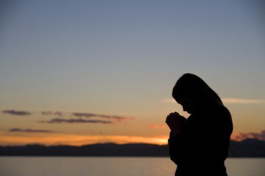 A Teenage Girl Prays At Sunset clipart