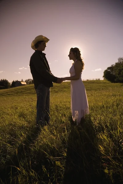 Young Man And Woman In Field Holding Hands — Stock Photo, Image