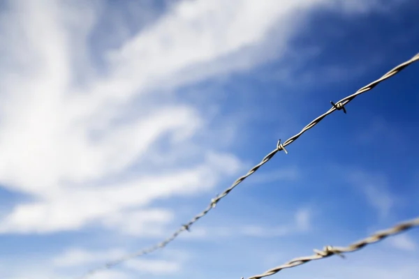Prikkeldraad hek en blauwe hemel — Stockfoto