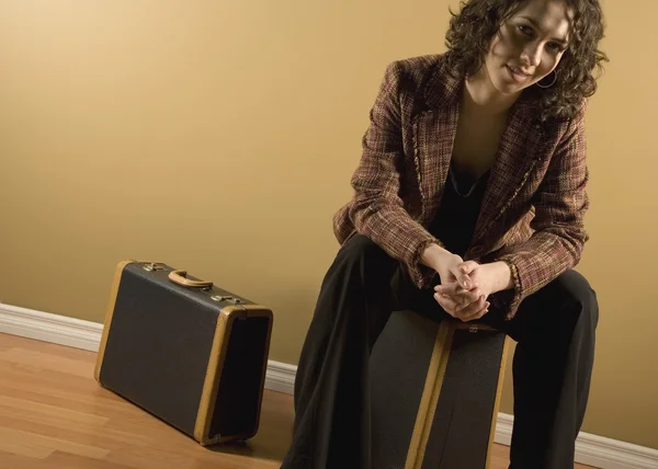 Frau sitzt auf Koffer — Stockfoto