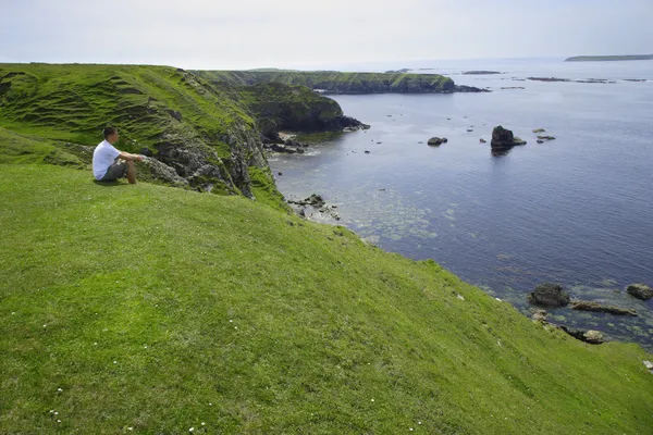 Condado de Donegal, Irlanda, Hombre sentado cerca de la costa — Foto de Stock