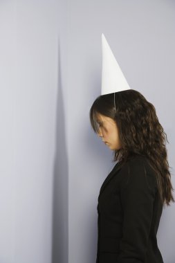 Woman Facing Corner With Dunce Cap clipart