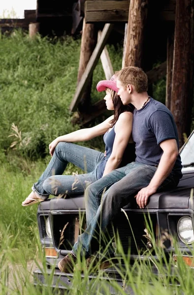 Couple Sitting On The Hood Of A Vehicle — Stock Photo, Image