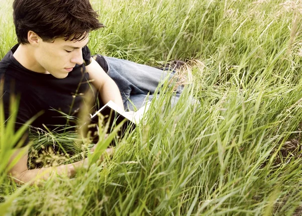 Человек, читающий книгу в траве — стоковое фото