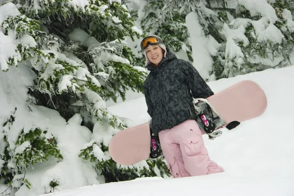 Una giovane donna che trasporta uno snowboard — Foto Stock