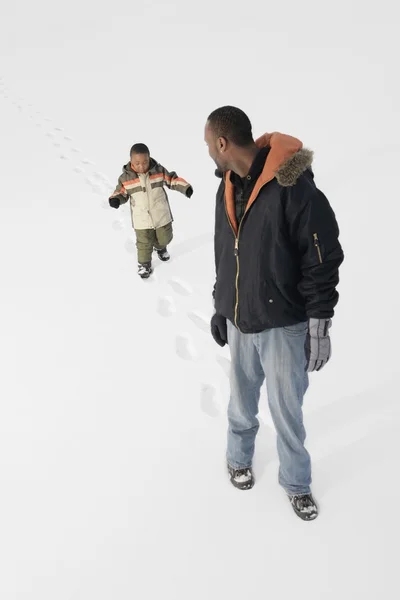 Niño siguiendo las huellas de papá en la nieve — Foto de Stock