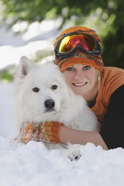 Молодая девушка лежит с собакой в снегу — стоковое фото