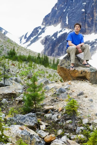 Vista frontal de un hombre sentado en la roca —  Fotos de Stock