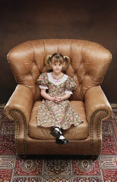 Menina sentada em poltrona grande — Fotografia de Stock