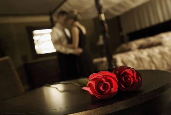 Casal abraçando com rosas na mesa — Fotografia de Stock