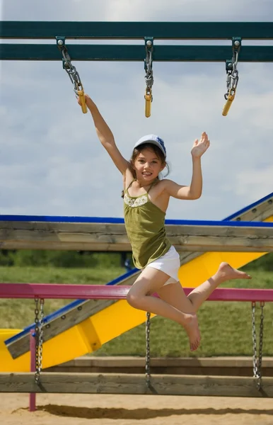 Meisje swingen op monkey bars — Stockfoto