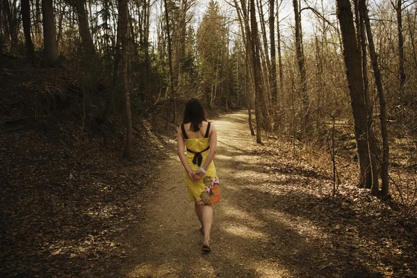 Mladá žena chůze podél cesty — Stock fotografie