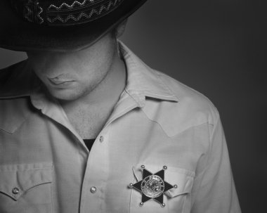 Cowboy Looking Down Under Hat With Sheriff's Badge On Shirt clipart