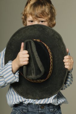 Young Boy Hiding Part Of Face With Large Cowboy Hat clipart