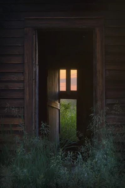 Tür zum verlassenen Haus mit warmem, einladendem Fensterlicht — Stockfoto