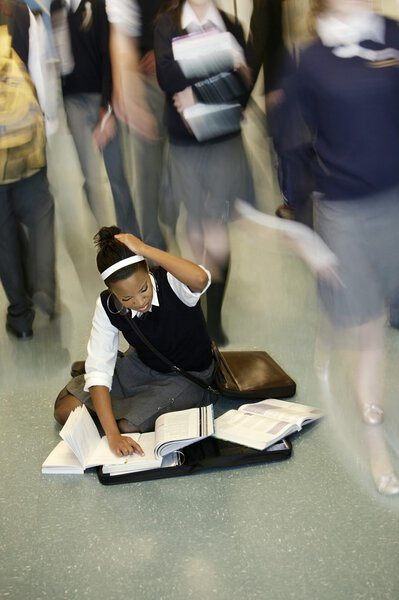 Teenage Girl Doing Homework In Middle Of School Hall