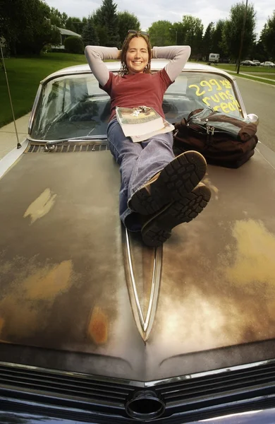 Vista frontale di una ragazza che posa sul cofano di un'auto in vendita — Foto Stock