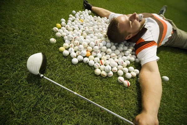 Ein Mann auf Golfbällen liegend — Stockfoto