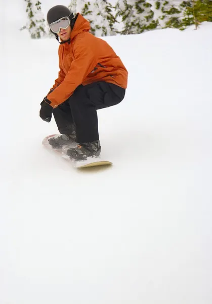 Snowboarder fährt verschneiten Hügel hinunter — Stockfoto