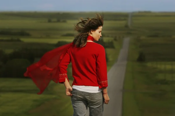 Alanlarla çevrili yolda yürüyen kadın — Stok fotoğraf