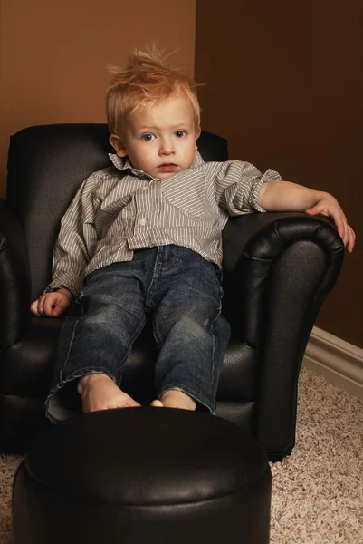 Jongen zittend in een stoel — Stockfoto