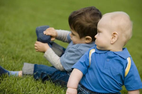 Due ragazzi seduti su erba — Foto Stock
