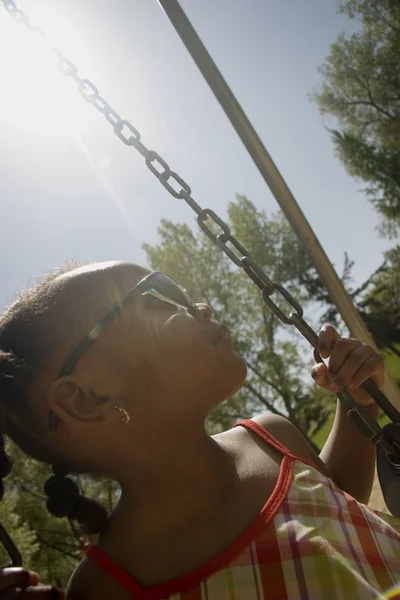 Chica joven sentada en el columpio en el parque — Foto de Stock