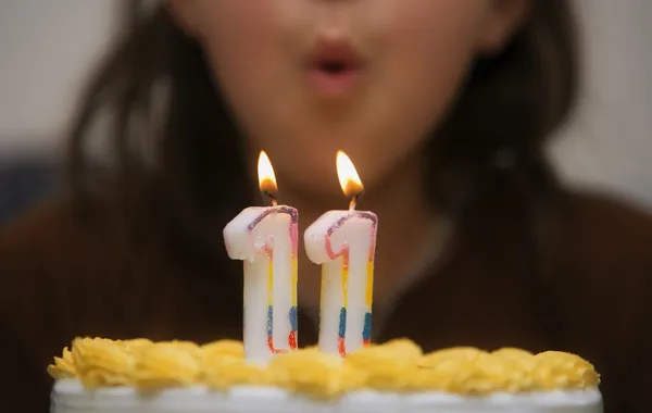 Menina soprando velas em um bolo de aniversário — Fotografia de Stock