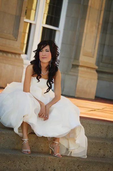 Bruden som sitter på utsidan steg i klänning — Stockfoto