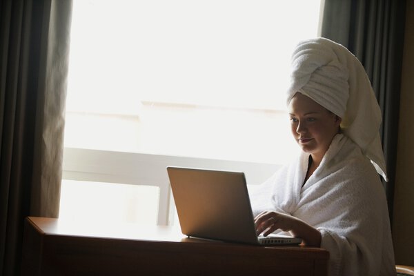 A Woman In A Bathrobe Using A Laptop